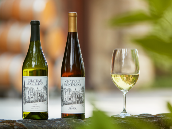 Chardonnay and Riesling bottles with full glass of wine